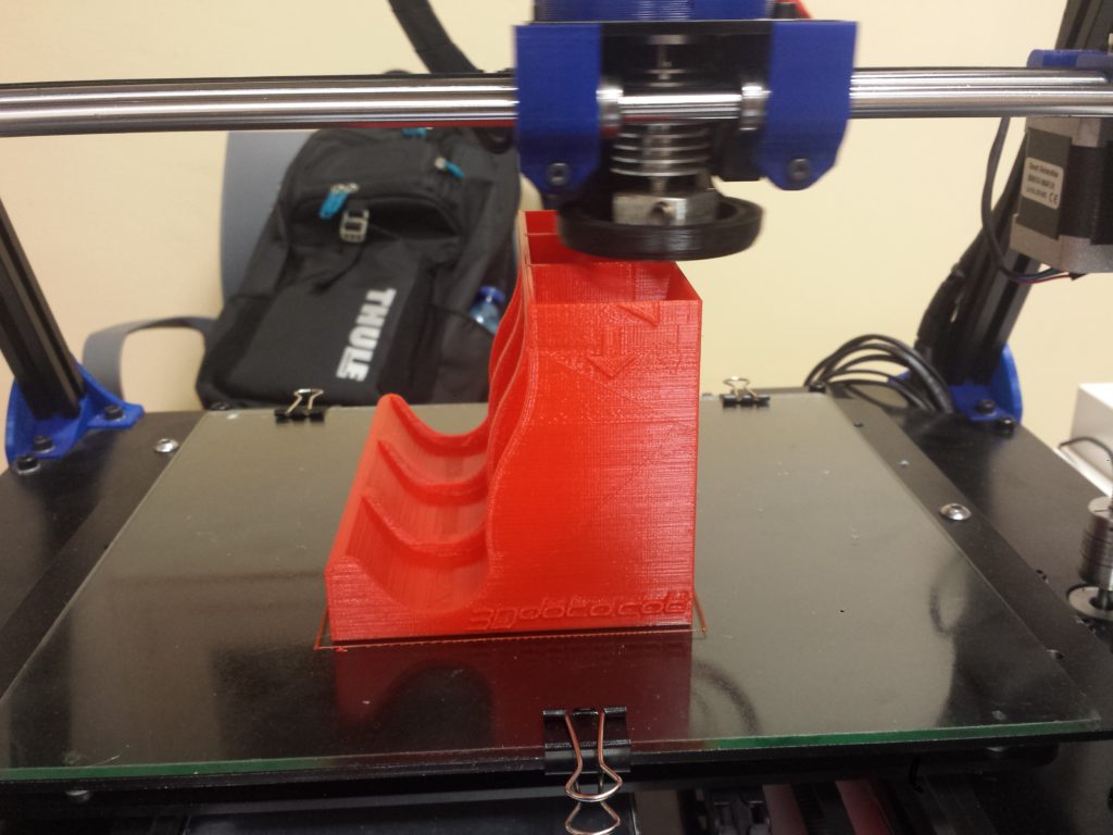 Impressora 3D treballant sobre una peça ja parcialment impresa.